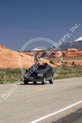 Automobile with mountain bike on a bike rack traveling on US highway 191 south of Moab, Utah.
