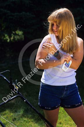 Teenage girl applying sunscreen to her arm.