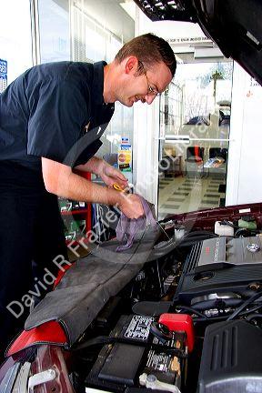 Automechanic checking the oil in a car.