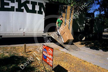 A moving truck and mover unloading boxes with a dolly in Boise, Idaho.