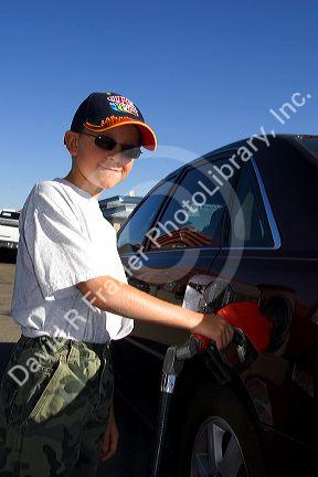 A nine year old boy pumps gasoline into a car at a gas station in Boise, Idaho. MR