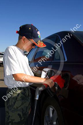 A nine year old boy pumps gasoline into a car at a gas station in Boise, Idaho. MR