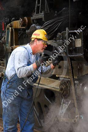 Brakeman greases bearings of historic Challenger locomotive steam engine.