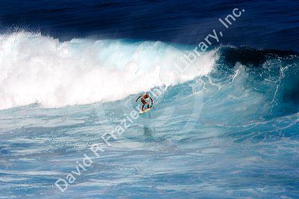 Surfing on waves in the pacific ocean off the island of Maui, Hawaii.