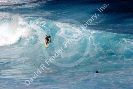 Surfing on waves in the pacific ocean off the island of Maui, Hawaii.