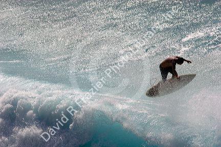 Surfing on waves in the pacific ocean off the island of Maui, Hawaii.