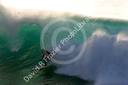 Surfing on waves in the pacific ocean off the island of Maui, Hawaii.
