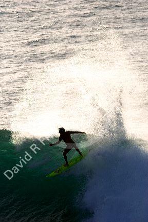 Surfing on waves in the pacific ocean off the island of Maui, Hawaii.