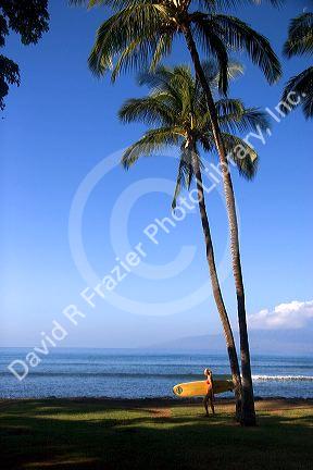 Girl walking with surfboard on the island of Maui, Hawaii.