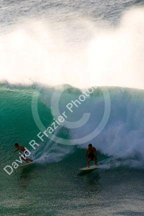 Surfing on waves in the pacific ocean off the island of Maui, Hawaii.