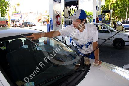 Attendant washing a car windshield at a gas station in Argentina.