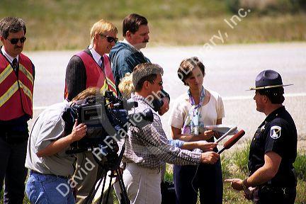 Television reporters interview an Idaho State Trooper.