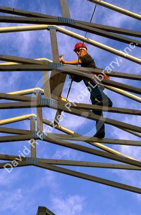 Construction worker using wood trusses for roof frame in Boise, Idaho.