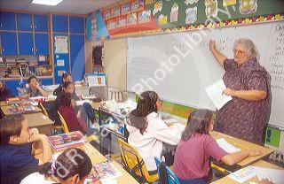 School teacher stands in front of a multi ethnic elementary school class.