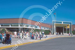 The exterior of White Pine elementary school building with children standing out front waiting for school bus.