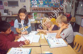 Elementary school teacher helping a group of students with their school lesson.