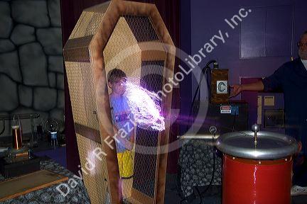 A boy in a wire cage demonstrating a Tesla coil with lightning at the Discovery Center in Little Rock, Arkansas.