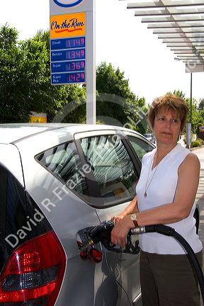 Woman fueling a car at a gas station in Friesing, Germany. MR