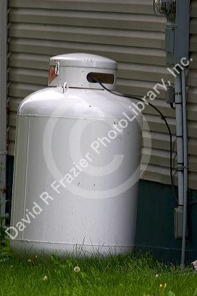 Propane fuel tank outside a house with supply line.