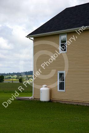 Propane fuel tank outside a house with supply line.