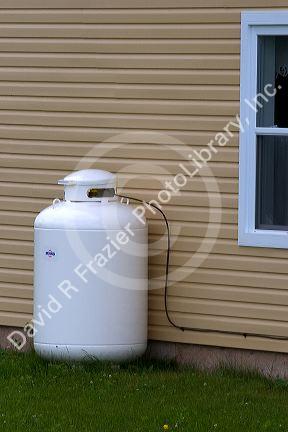 Propane fuel tank outside a house with supply line.