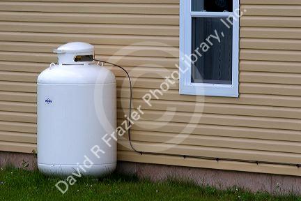 Propane fuel tank outside a house with supply line.