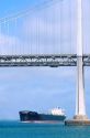 Cargo ship passing beneath San Francisco Bay Bridge.