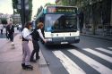 Girls crossing the street wearing rollerblades while a public bus waits in Paris, France.