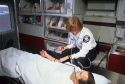 A female paramedic examines a patient inside an ambulance.
