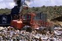 A large dumpster unloads trash while a bulldozer moves it at a sanitary landfill in Boise, Idaho.