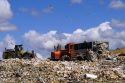 A large dumpster unloads trash while bulldozers move it at a sanitary landfill in Boise, Idaho.