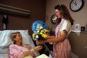Volunteer candy striper delivers flowers to a hospital patient.