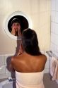 Young woman uses a mirror while washing her face. MR