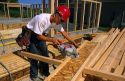 Construction worker using a power saw to cut an I-beam to size.