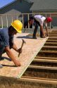Construction workers installing the tongue and groove sub-floor of a new home.