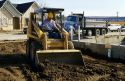 Construction worker using a bobcat type loader to backfill a foundation in Boise, Idaho.