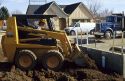 Construction worker using a bobcat type tractor to backfill a foundation in Boise, Idaho.
