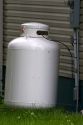 Propane fuel tank outside a house with supply line.