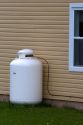 Propane fuel tank outside a house with supply line.