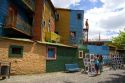 Paintings being sold on Caminito street in front of colorful buildings in the La Boca area of Buenos Aires, Argentina.