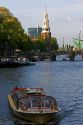 Canal boat on the Amstel River with Montelbaans Tower in the background, Amsterdam, Netherlands.