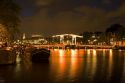 Skinny Magere drawbridge lit up at night on the Amstel River in Amsterdam, Netherlands.