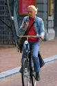 Woman using a cell phone while riding a bicycle in Amsterdam, Netherlands.