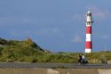 People ride bicycles past the Nieuwpoort Lighthouse at Nieuwpoort in the province of West Flanders, Belgium.