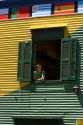 Woman looking out the window of a colorful building in the La Boca barrio of Buenos Aires, Argentina.