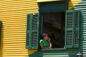 Woman standing in the window of a colorful building in the La Boca barrio of Buenos Aires, Argentina.