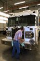 Worker cleaning a newly manufactured fire truck chassis at Spartan Motors in Charlotte, Michigan.