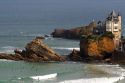 Surfing Cote de Basque below a castle in the Bay of Biscay at the town of Biarritz, Pyrenees Atlantiques, French Basque Country, Southwest France.