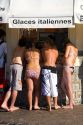 Teens buy ice cream from a vendor at the beach in the town of Saint-Jean-de-Luz, Pyrenees Atlantiques, French Basque Country, Southwest France.