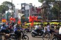Vietnamese people ride motorbikes past Kentucky Fried Chicken sign and communist flags in Ho Chi Minh City, Vietnam.